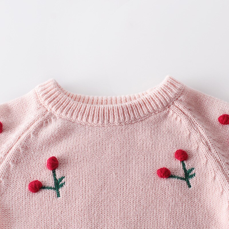 Close-up of cherry embroidery on pink knit