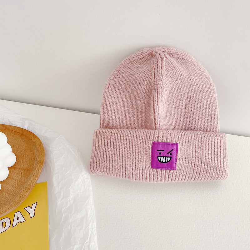 Pink knit beanie with purple smiley patch