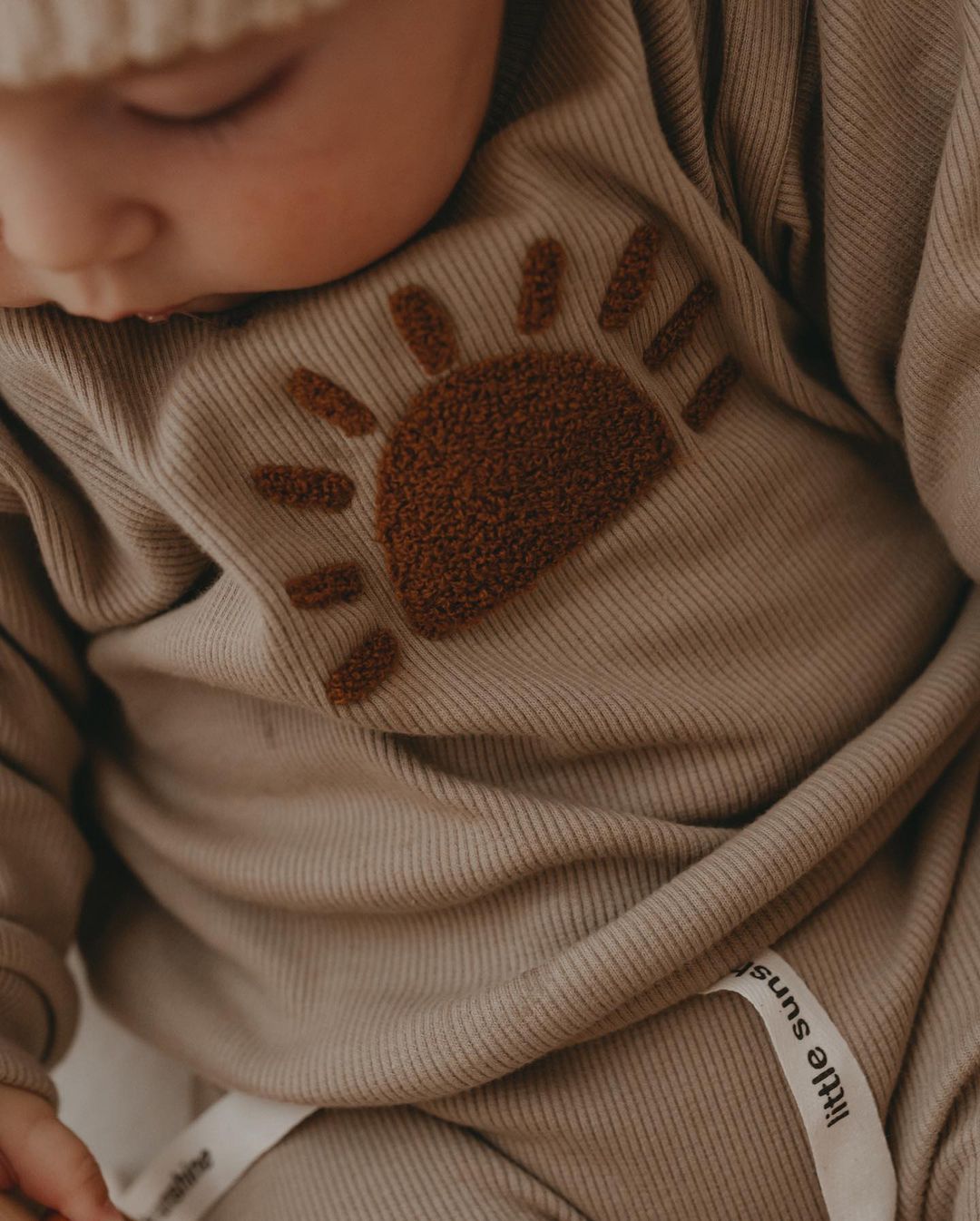 Close-up of the sun motif on a khaki baby sweatshirt