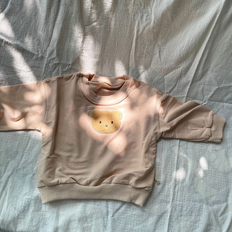 Taupe bear patch sweatshirt in sunlight