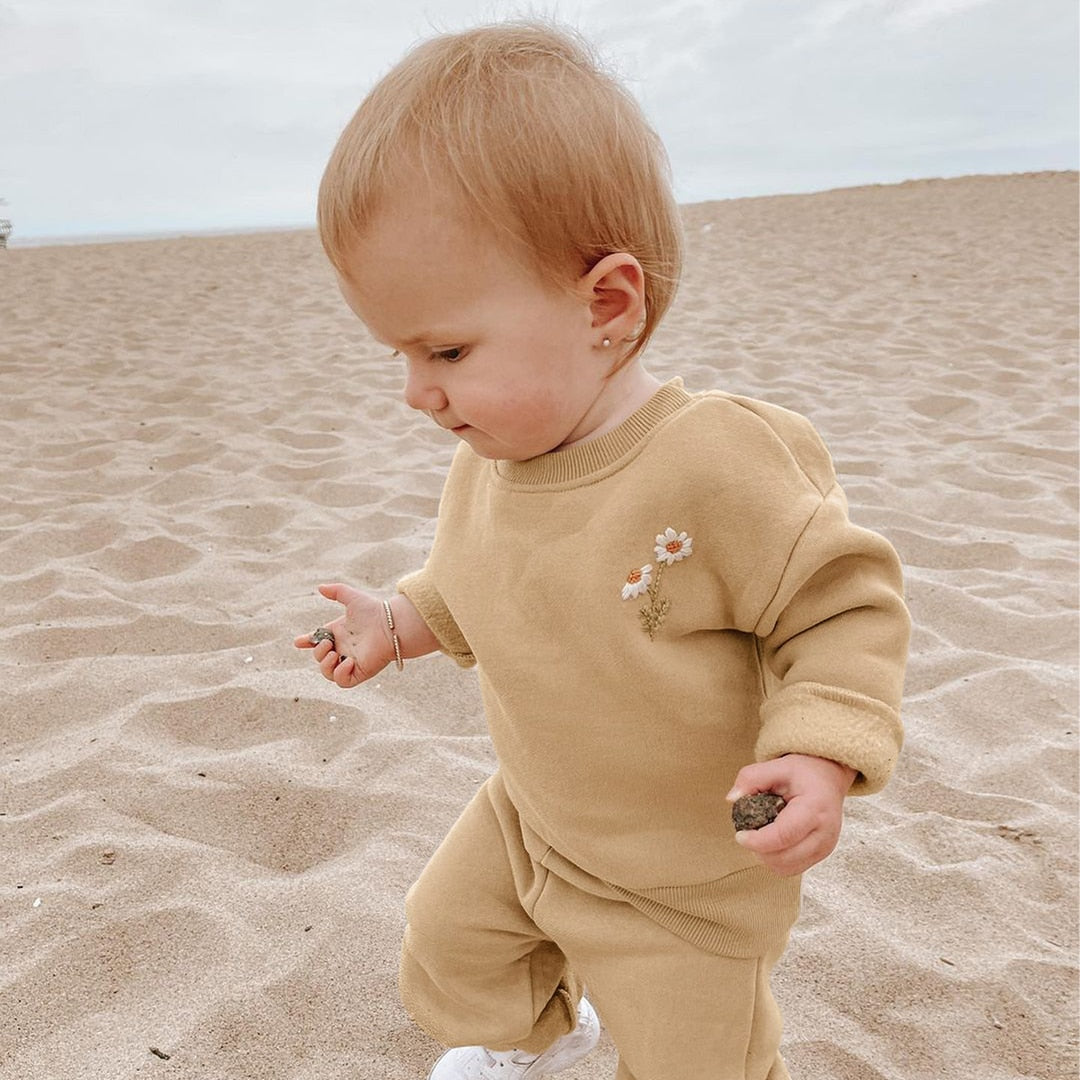 Toddler wearing khaki daisy set on the beach