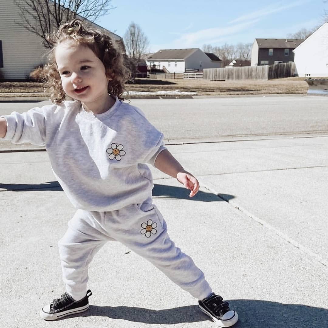 Toddler running outdoors in a grey daisy sweatshirt set