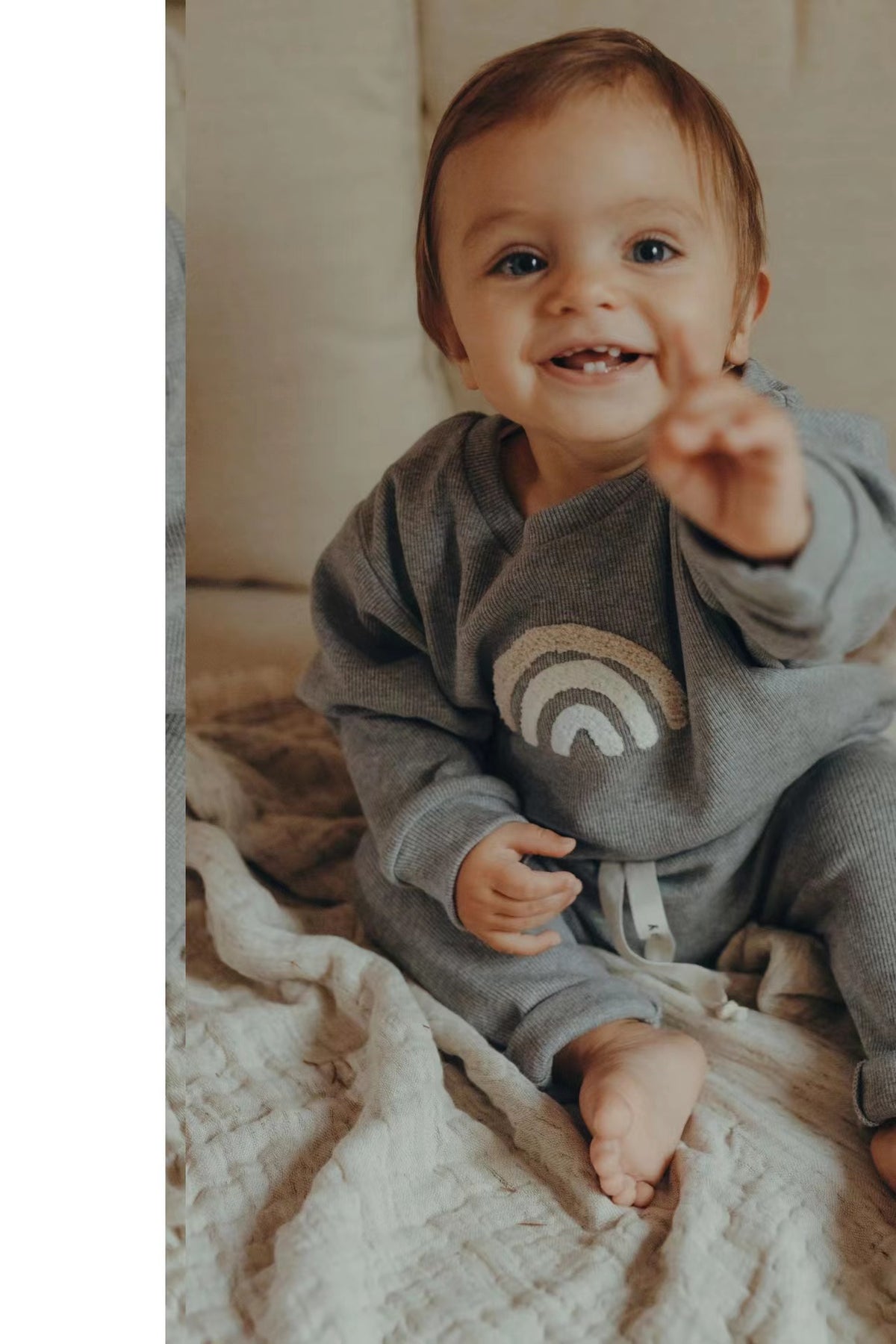 Smiling toddler in a grey rainbow tracksuit set