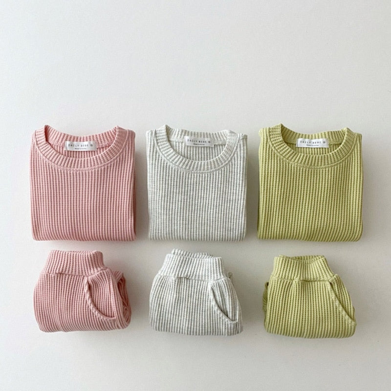 Pink, gray and green waffle knit tracksuits laid flat